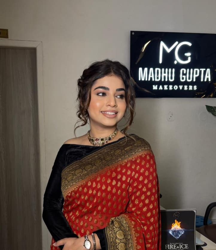 Madhu Gupta wearing a red and black saree with soft dewy party makeup, neutral eyes and nude lips at MG Makeovers Studio in Gurgaon.