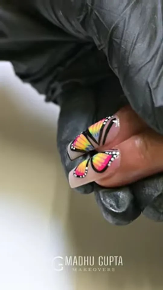 Video thumbnail: gloved hand holding a finger with a rainbow butterfly design painted on a nude nail extension