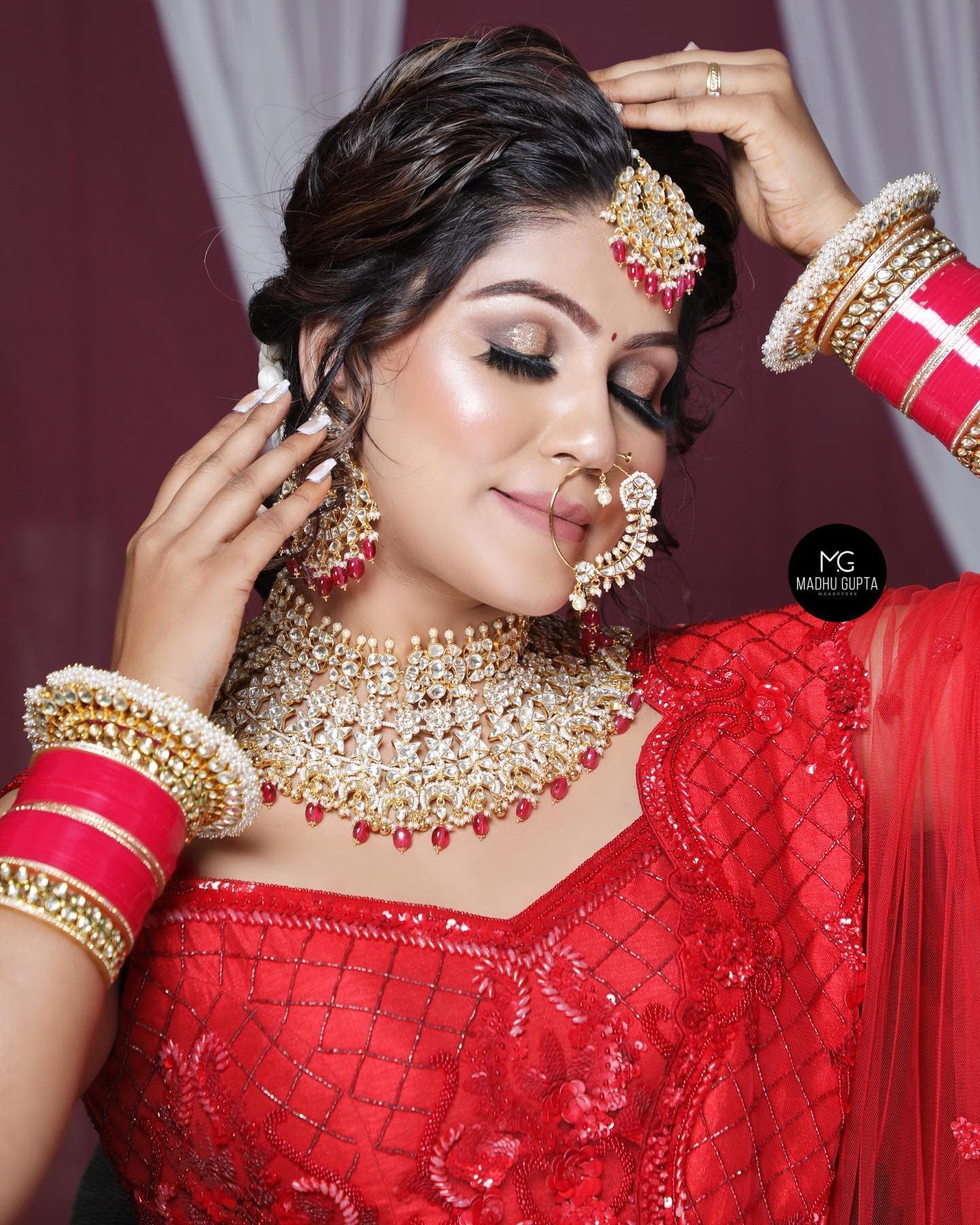 Bride in a red lehenga with bridal makeup by MG Makeovers