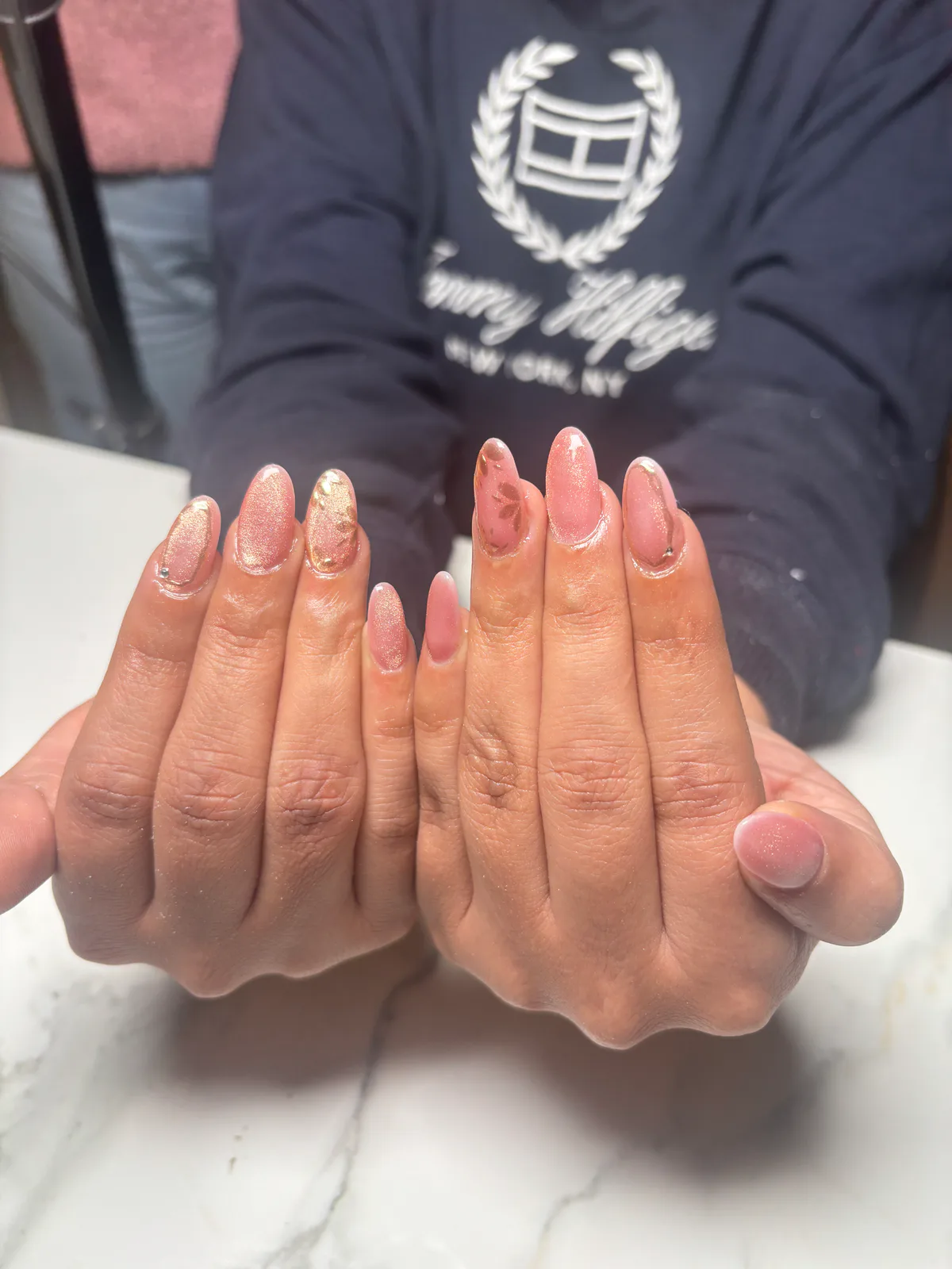 Pink cat-eye chrome nail extensions with delicate floral accents by MG Makeovers