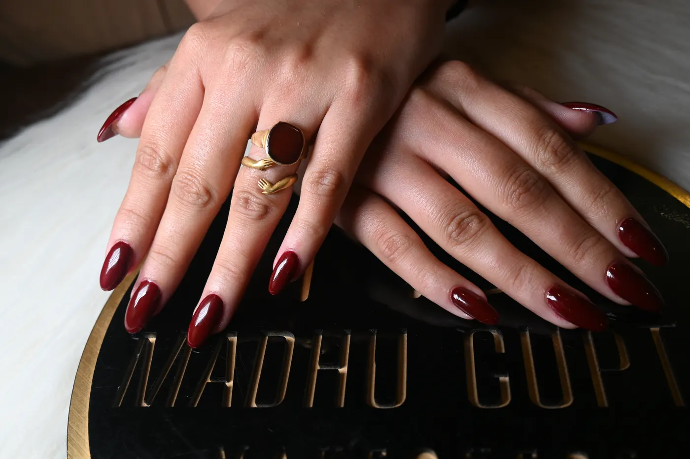 Close-up of burgundy red almond nail art at MG Makeovers